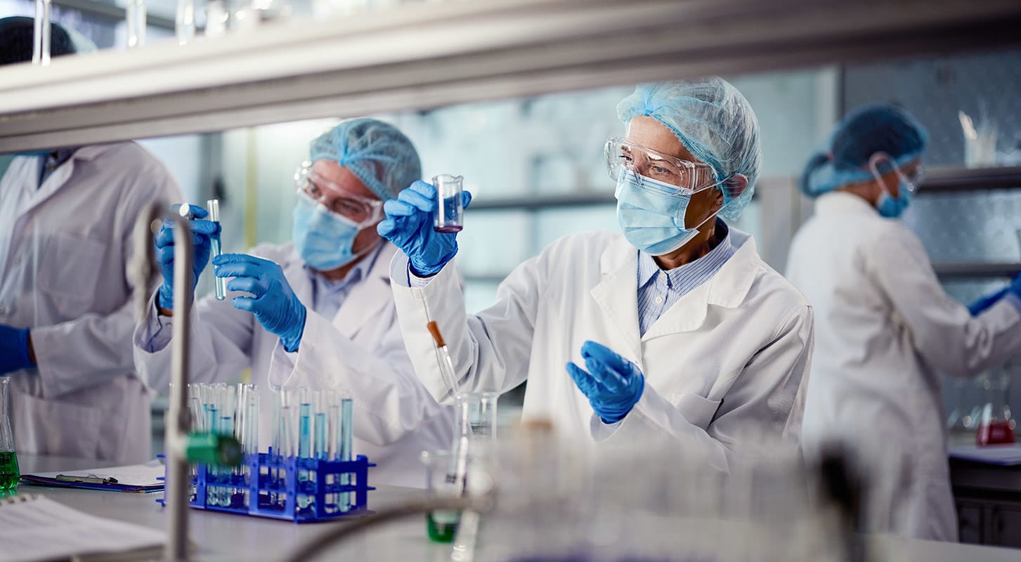 A team of researchers in lab coats and masks, focused on their work in a laboratory setting.